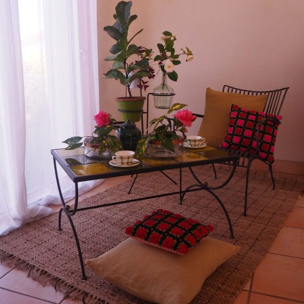 ambiance brocante fauteuil metal table fer forge tapis coussins vase fleurs support pots fleurs
